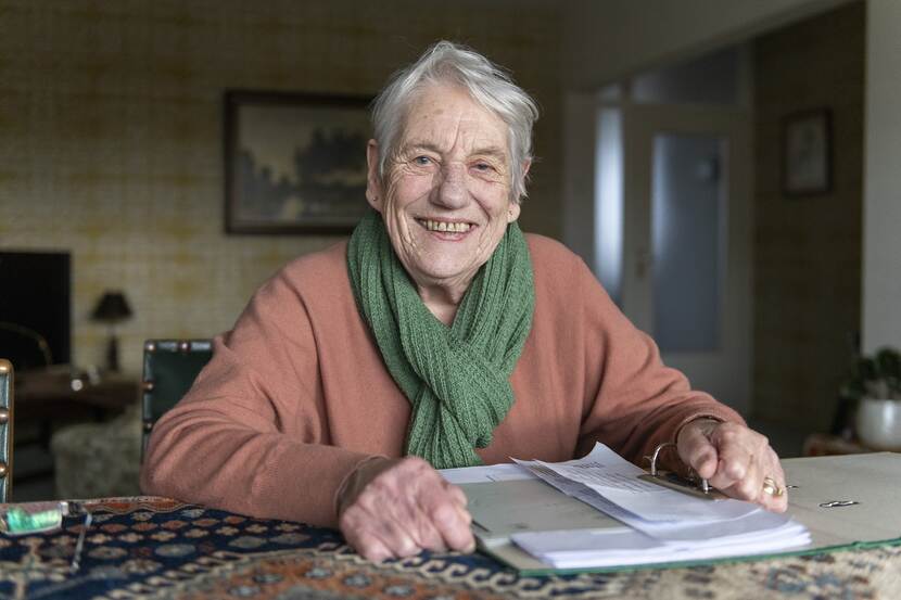 foto van een oude dame met een map op tafel